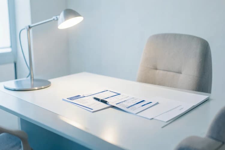Uma pessoa revisando atentamente um contrato ou lista de verificação em uma mesa, com uma caneta na mão, indicando o processo de avaliação e seleção de serviços.